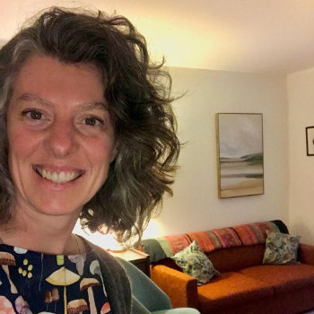 Instagram photograph: Geneva Jacobs smiling in a room with a sofa, cushions and framed artwork.