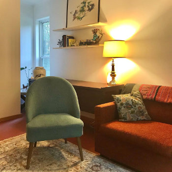 Instagram photograph: a green chair beside a sofa, cushions, a lit table lamp and wall shelves.